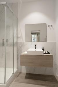 La salle de bains blanche est pourvue d'un lavabo et d'un miroir. dans l'établissement Hygge House, à Lisbonne