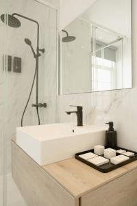 La salle de bains blanche est pourvue d'un lavabo et d'une douche. dans l'établissement Hygge House, à Lisbonne