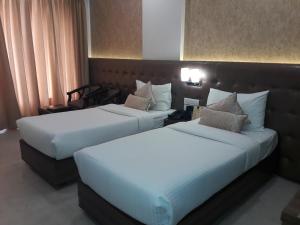 two beds in a hotel room with white sheets at Hotel Ramaya in Gwalior