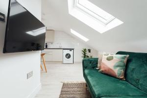 a living room with a green couch and a flat screen tv at Contemporary 1 Bedroom Loft in Ilford, London in Ilford