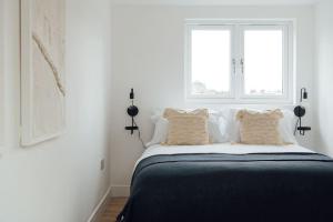 a white bedroom with a bed with two windows at Contemporary 1 Bedroom Loft in Ilford, London in Ilford