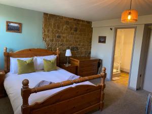 Un dormitorio con una gran cama de madera y una lámpara. en The Hollybush Inn and B&B, en Priors Marston