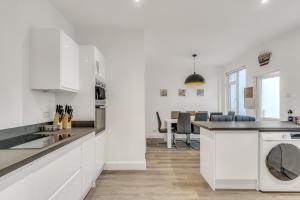 a kitchen with white cabinets and a table with chairs at Park House - Central spacious 4 bedroom Edwardian house, with games room in the heart of Plymouth in Plymouth