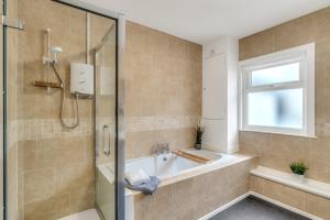 a bathroom with a tub and a shower with a window at Park House - Central spacious 4 bedroom Edwardian house, with games room in the heart of Plymouth in Plymouth