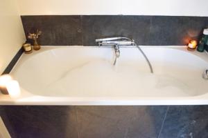 PERFECT B&B MIDDLE OF AMSTERDAM في أمستردام: حوض استحمام مع صنبور في الحمام
