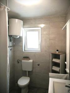 a bathroom with a white toilet and a window at Apartment Karlo - city center in Pag