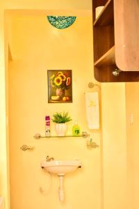 a bathroom with a sink and a vase of flowers at Classic Studio Milimani - Wi-Fi and Parking in Kisumu