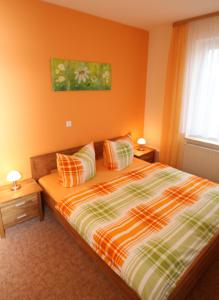 Schlafzimmer mit orangefarbenen Wänden und einem Bett mit Kissen in der Unterkunft Gasthaus Forelle in Thale