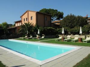 einen Pool mit Stühlen und Sonnenschirmen neben einem Haus in der Unterkunft Attractive apartment in Castiglione del Lago with pool in Castiglione del Lago