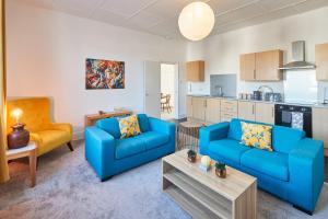 a living room with two blue couches and a kitchen at Beautiful Sea View Apartment in St Leonards on Sea in St. Leonards