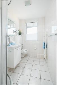 La salle de bains blanche est pourvue de toilettes et d'un lavabo. dans l'établissement Windrose 16, à Norderney