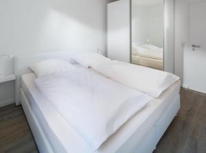 uma cama branca num quarto com um espelho em weitSicht em Norderney