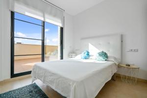 a white bedroom with a bed with a large window at Ferran in Deltebre