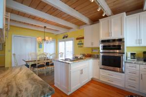 a large kitchen with white cabinets and a table at Holden Jeanie in Holden Beach