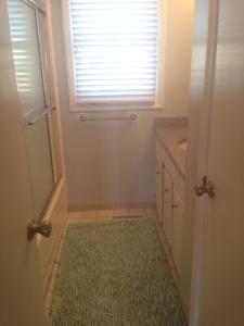 een kleine badkamer met een deur met een groen tapijt bij Dune Deck South - Duplex in Holden Beach