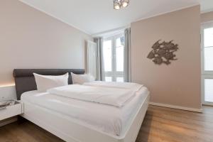 ein weißes Schlafzimmer mit einem großen Bett mit weißer Bettwäsche in der Unterkunft Sonne 3 in Norderney
