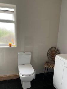 a bathroom with a toilet and a window and a chair at Holbrook house in Cherry Hinton