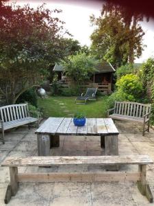 two benches and a wooden picnic table in a yard at Holbrook house in Cherry Hinton