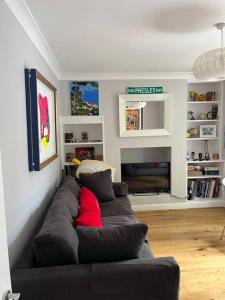 a living room with a black couch with a red pillow at Holbrook house in Cherry Hinton