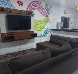 a living room with a couch and a flat screen tv at Casa com Piscina e 3 Quartos Climatizados 8km do Centro in Palmas