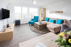 een woonkamer met een bank en blauwe stoelen bij Sommerdeich4you in Norderney