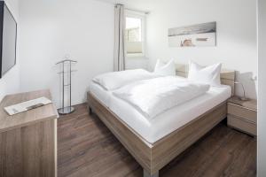 een slaapkamer met een groot bed met witte lakens bij Sommerdeich4you in Norderney