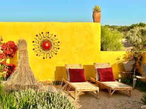 twee stoelen en een muur met een muurschildering van een zon bij Éco-Ranch Salomé in Sidi Kaouki