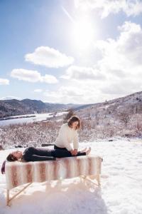 a woman and a man sitting on a bench in the snow at Wanderer Studio, AN OFF GRID MOUNTAIN Guest Studio With Fantastic Views in Glenwood Springs