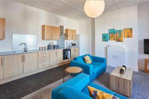a living room with a blue couch and a kitchen at Beautiful Sea View Apartment in St Leonards on Sea in St. Leonards +15 photos