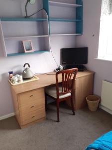 a wooden desk with a chair and a computer at Home from home, single room with virgin channels, Wifi & free parking in Poole