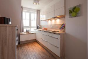 een keuken met witte kasten en een houten vloer bij Villa Brunnenhof 06 in Norderney