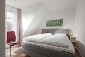 een slaapkamer met een groot bed en een rode stoel bij Villa Brunnenhof 06 in Norderney