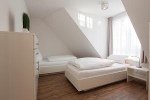 een witte kamer met een bed en een raam bij Villa Brunnenhof 06 in Norderney