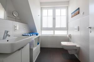 een witte badkamer met een wastafel en een toilet bij Villa Brunnenhof 06 in Norderney