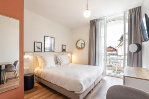ein Schlafzimmer mit einem Bett und einem großen Fenster in der Unterkunft Apparthotel Privilodges Le Royal in Annecy