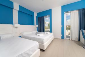 a hotel room with two beds and blue walls at Terrazze Naos in San Leone