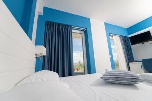 a bedroom with a white bed with blue walls and a window at Terrazze Naos in San Leone