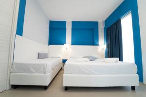 two beds in a room with blue and white at Terrazze Naos in San Leone