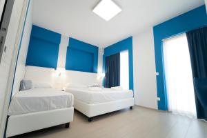 two beds in a room with blue and white walls at Terrazze Naos in San Leone