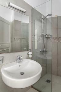 een badkamer met een witte wastafel en een douche bij Alkyoni Studios in Ándros