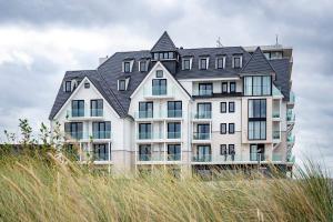 a large white building with a black roof at By Sea, Full Sea View, balcony, use of hotel Pool and Sauna in Cadzand