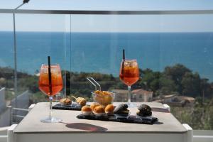 a table with two glasses of wine and pastries at Terrazze Naos in San Leone