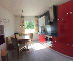 a kitchen with red cabinets and a table and chairs at Ferienwohnung Renate Pfaller in Riedenburg