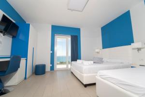 a blue and white bedroom with two beds and a window at Terrazze Naos in San Leone