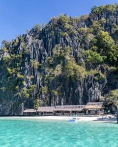 a building on a beach in front of a mountain at NaturesWay/TRAVELCORON in Coron