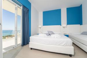 a bedroom with two beds and a large window at Terrazze Naos in San Leone