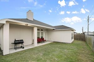 a white house with a grill in a yard at Luxurious Coastal Retreat Brand New 4BR Home with Fast WiFi, 15 min to Beach! in Corpus Christi