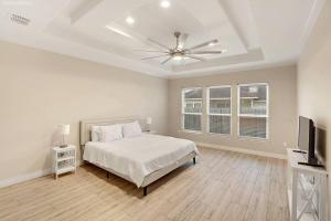 ein weißes Schlafzimmer mit einem Bett und einem Deckenventilator in der Unterkunft Luxurious Coastal Retreat Brand New 4BR Home with Fast WiFi, 15 min to Beach! in Corpus Christi