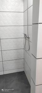y baño con ducha y paredes de azulejos blancos. en Gajówka Świt, 