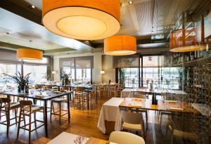 un restaurante con mesas, sillas y ventanas grandes en Qgat Restaurant Events & Hotel, en Sant Cugat del Vallès